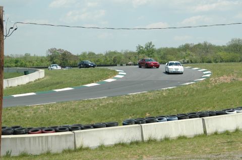 1993 Ford Mustang - Multiple cars are seen on a race track during a sunny day.