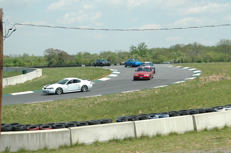 White Ford Mustang with black racing stripes on a track