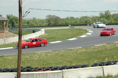 1993 Ford Mustang - A red 1993 Ford Mustang races on a track, with another car visible in the background.