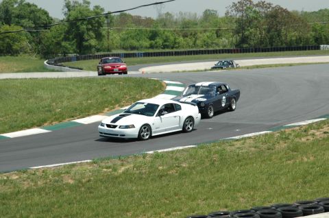 1993 Ford Mustang - A white Ford Mustang races on a track alongside other vehicles.
