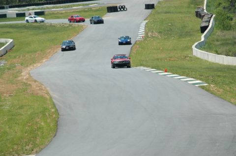1993 Ford Mustang - Multiple cars are seen on a race track during a sunny day.