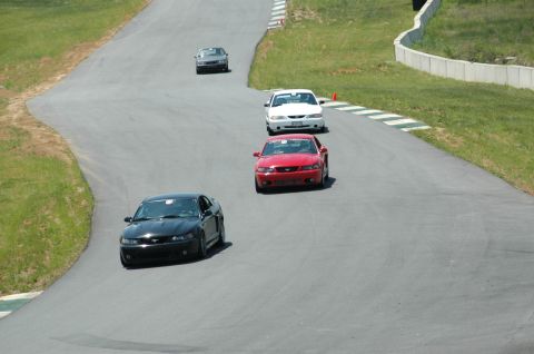 1993 Ford Mustang - Multiple Mustangs are seen on a race track during a sunny day.
