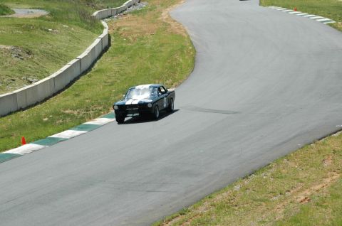 1993 Ford Mustang - A black 1967 Ford Mustang with white racing stripes navigates a curve on a race track.