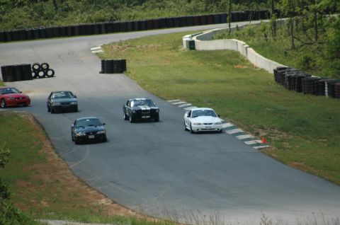 1993 Ford Mustang - Multiple Ford Mustangs race on a track, with a white Mustang in the foreground.