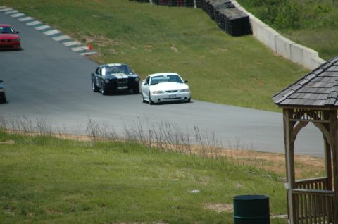 1993 Ford Mustang - Multiple Ford Mustangs race on a track, including a white 1996 GT and a black classic model.