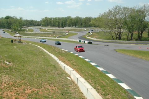 1993 Ford Mustang - A red 1993 Ford Mustang navigates a turn on a sunny day at the racetrack.
