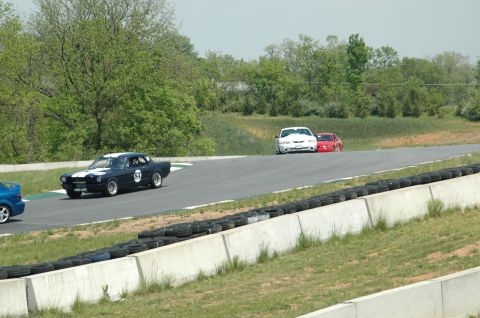 1993 Ford Mustang - Multiple cars compete on a race track with trees and barriers visible.