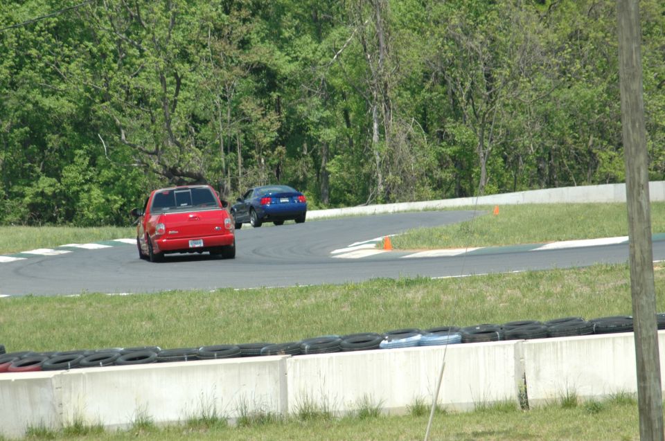 Red pickup truck and blue car on a racetrack, rear view