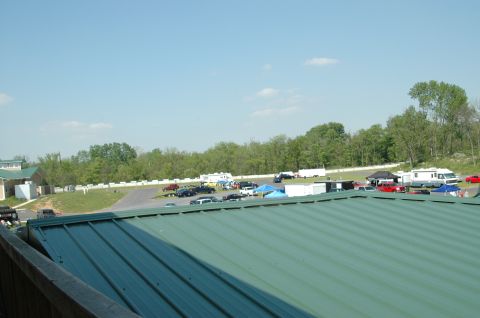 1993 Ford Mustang - A wide view of a parking area with various vehicles and tents, set against a backdrop of trees.