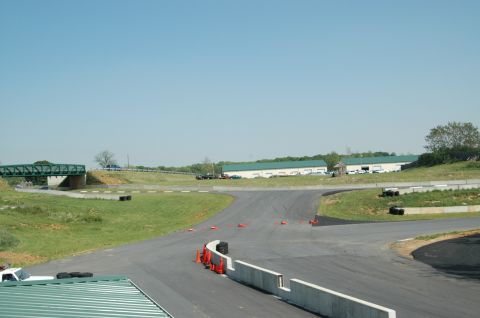 1993 Ford Mustang - A view of a race track on a clear day, showing the track, barriers, and surrounding buildings.
