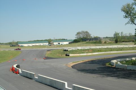 1993 Ford Mustang - A view of a race track with several cars visible in the distance and buildings in the background.