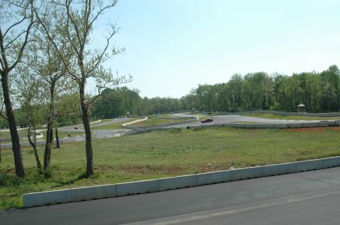 1993 Ford Mustang - A scenic view of a race track with several cars in motion under a bright, clear sky.