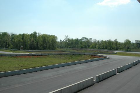 1993 Ford Mustang - A view of a winding race track with concrete barriers and surrounding trees on a clear day.