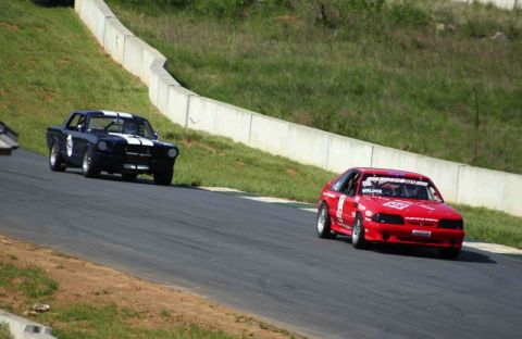 1993 Ford Mustang - A red 1993 Ford Mustang hatchback competes on a race track alongside another vehicle.