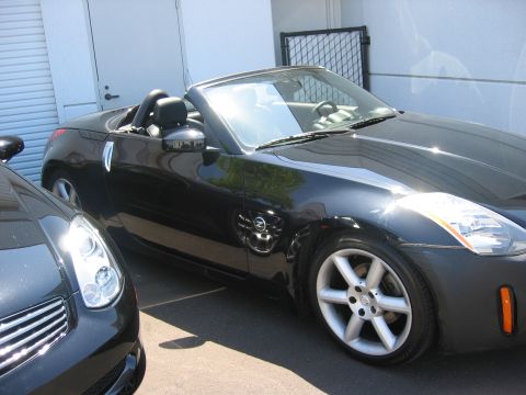 2004 Nissan 350Z - A black 2004 Nissan 350Z convertible is parked outdoors next to another vehicle.