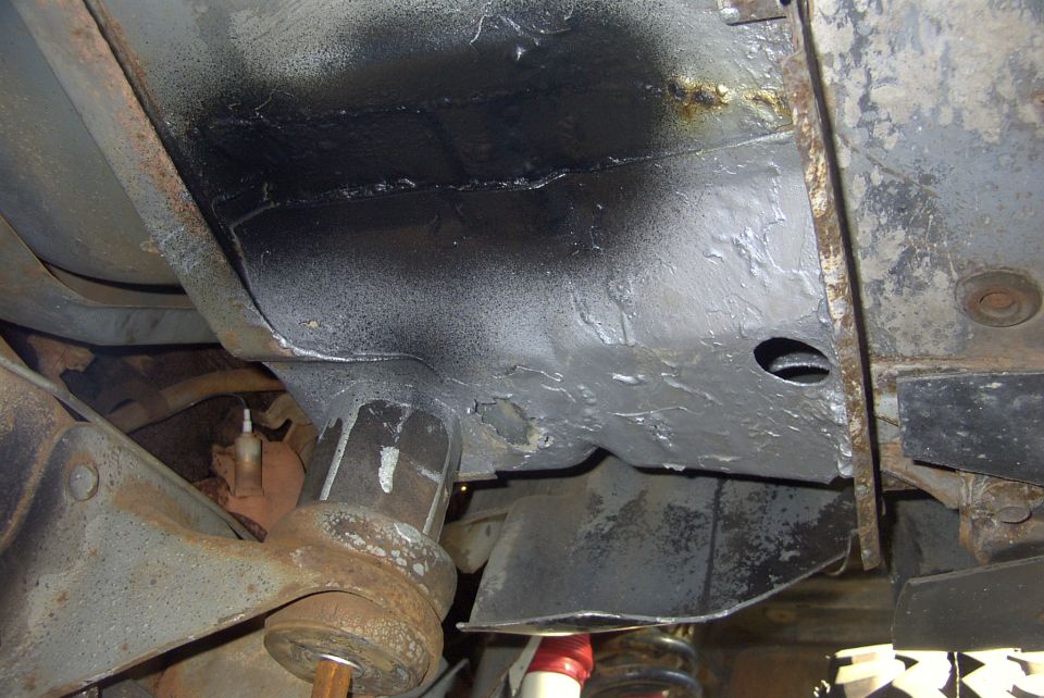 Underside of a vehicle showing frame and suspension components, some parts appear to have been painted
