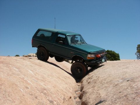 1996 Ford Bronco - This 1996 Ford Bronco navigates a challenging off-road trail under a clear blue sky.