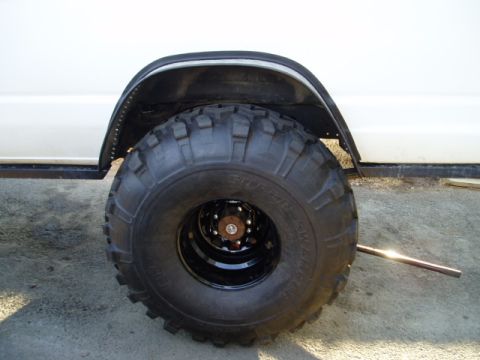 2000 Ford E350 - A close-up view of a modified wheel well and tire on a white van.