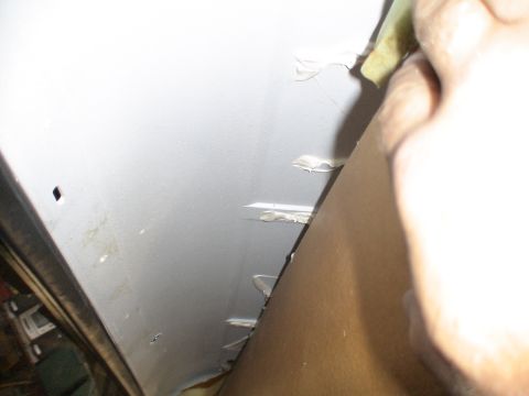 1993 Ford C-350 (Centurion Conversions) - A person is applying sealant to an interior panel, possibly for repair or insulation.