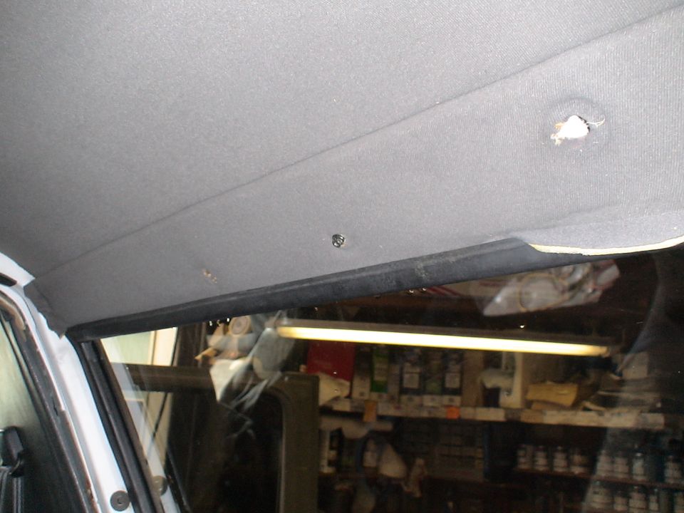 Interior headliner with visible screw holes and a black trim piece above the windshield