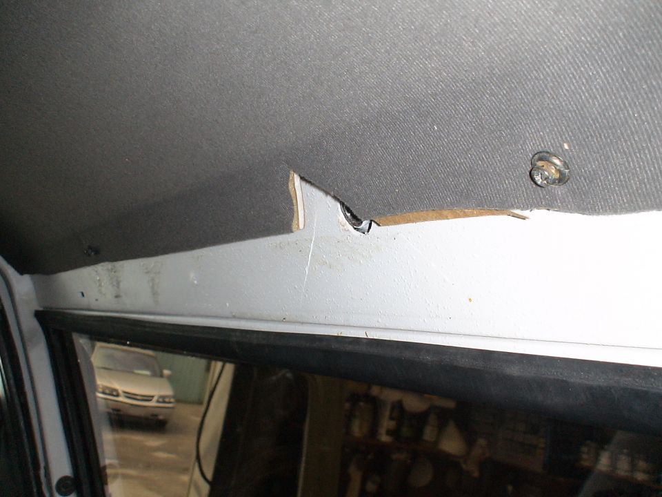 Interior view of damaged headliner and trim panel, with another car visible through the window