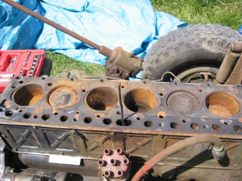 1991 Ford Explorer - A disassembled engine block sits outdoors with various engine components and a tire nearby.
