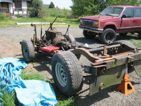 1991 Ford Explorer - A red 1991 Ford Explorer is parked beside a disassembled vehicle chassis outdoors.