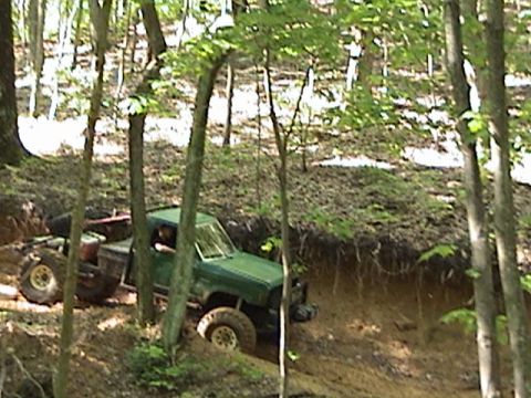 1996 Ford Bronco - A green truck navigates a muddy, wooded trail.