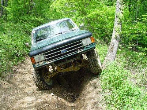 1996 Ford Bronco - This Ford truck is navigating a challenging off-road trail with steep inclines and rough terrain.