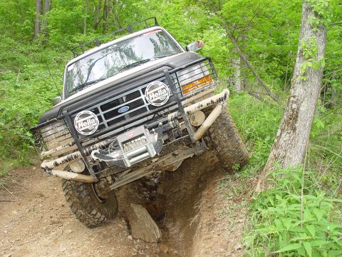 1996 Ford Bronco - Ford Bronco is shown off-roading on a dirt path with a winch mounted on the front bumper.