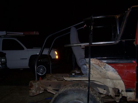 1979 Ford F-150 - Interior view of a modified truck with a roll cage, showing a seat and exposed metalwork. A white pickup truck is visible in the background.