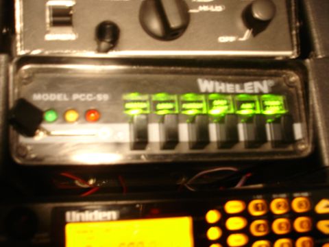 1999 Ford Crown Victoria - Close-up of a Whelen siren control panel, model PCC-59, showing illuminated buttons and status indicators.