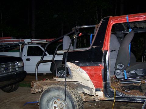 1979 Ford F-150 - A heavily modified off-road vehicle is shown in a state of disassembly, with a white pickup truck visible in the background.