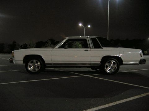 1985 Ford LTD Crown Victoria - Side view of a white 1985 Ford Crown Victoria parked in a lot after dark.
