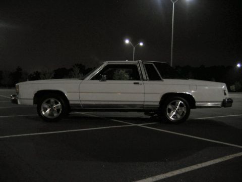 1985 Ford LTD Crown Victoria - Side view of a white 1985 Ford Crown Victoria LTD parked in a lot at night under streetlights.