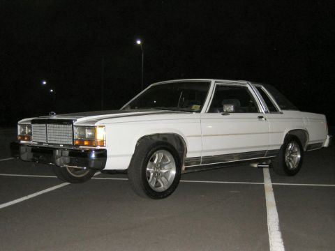1985 Ford LTD Crown Victoria - White two-door Ford LTD Crown Victoria coupe photographed at night in a parking lot, shown from the front three-quarter angle with aftermar…
