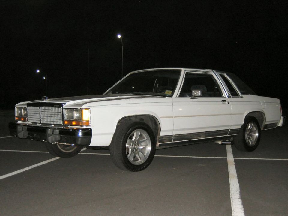 White two-door Ford coupe at night with alloy wheels in a parking lot