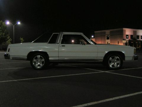 1985 Ford LTD Crown Victoria - Side view of a white 1985 Ford Crown Victoria LTD coupe parked in a lot after dark.