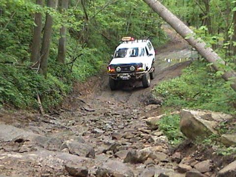 1996 Ford Bronco - This 1996 Ford Bronco navigates a challenging, rocky off-road path through a dense forest.