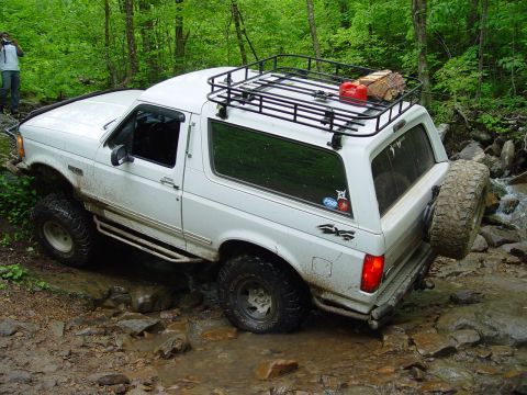 1996 Ford Bronco - This 1996 Ford Bronco is shown off-roading through a rocky stream with a roof rack carrying firewood and a gas can.