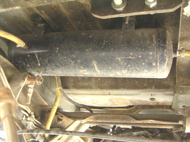 Black onboard air tank mounted under a vehicle with yellow air line and brass fittings