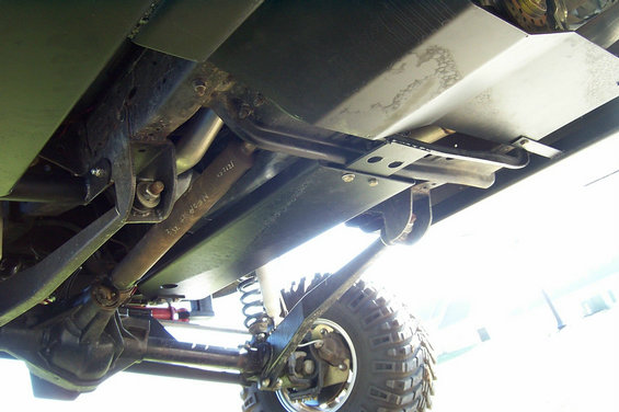 Underside of lifted 4x4 with bolt-on skid plates and red coilover shocks