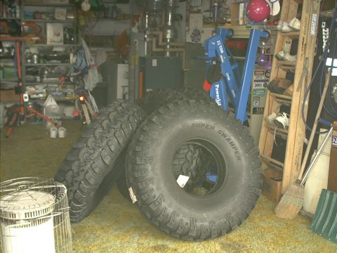 1978 Ford Bronco - Oversized Super Swamper tires are stored in a cluttered garage.