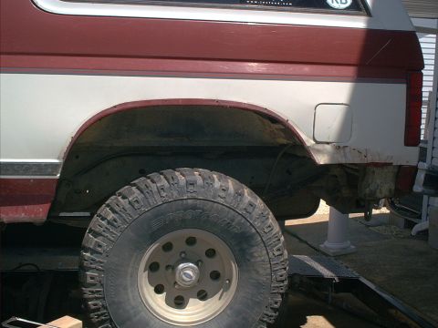 1986 Ford Bronco - Close-up of the rear wheel well and lower body panel of an SUV, showing off-road tires.