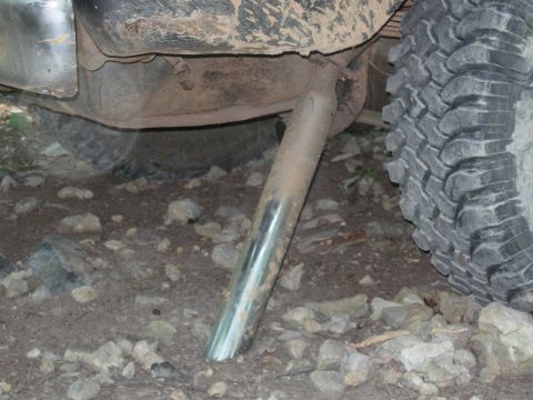 1995 Ford Bronco - Close-up view of an exhaust pipe and tire on a vehicle parked on rocky terrain.
