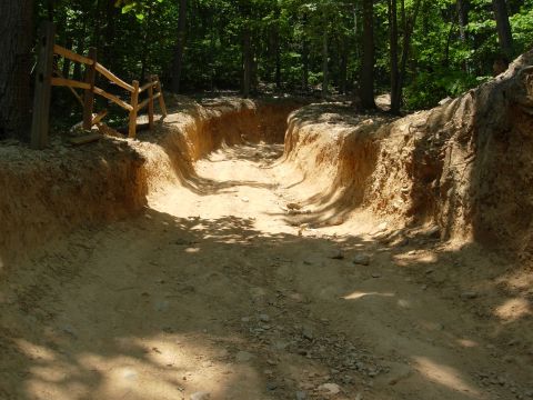 1995 Ford Bronco - A off-road trail winds through a wooded area, a wooden fence along the side.