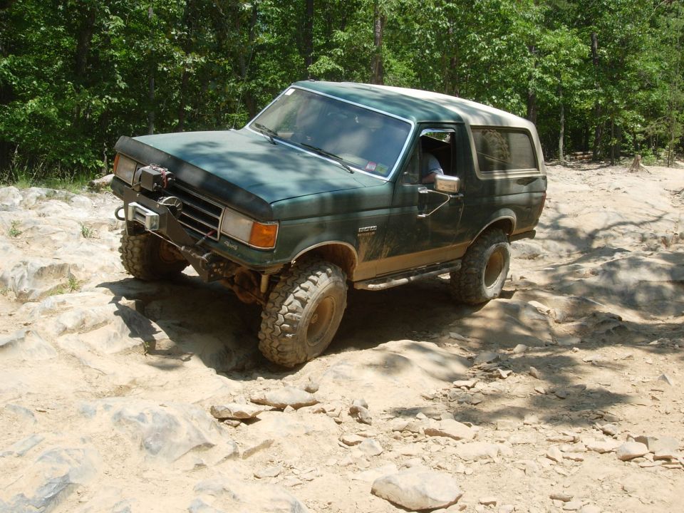 Green SUV with lifted suspension navigating rocky terrain