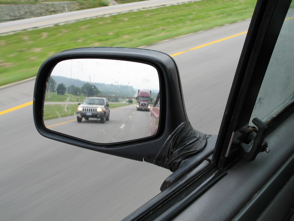 Jeep Cherokee in side mirror, semi-truck behind