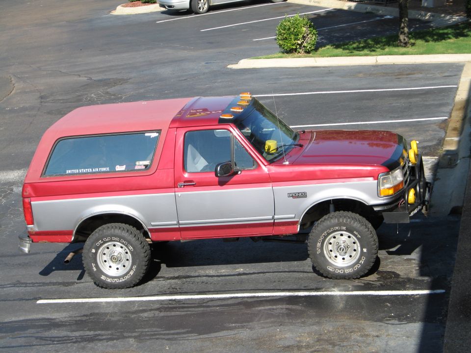 Red and silver two-door SUV with camper shell, "UNITED STATES AIR FORCE" sticker on rear window