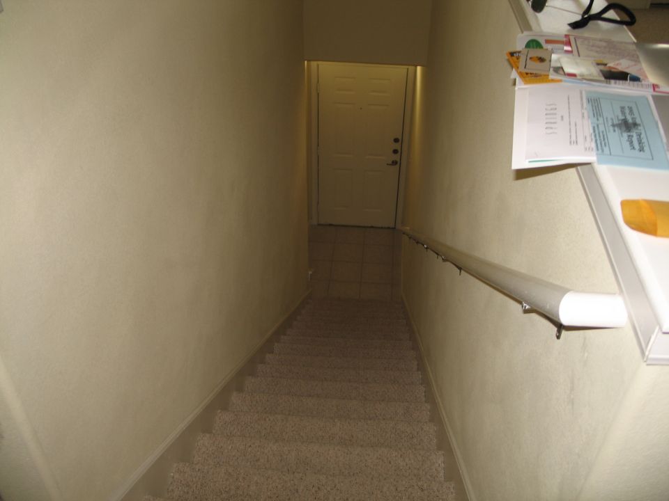 Interior staircase with a white door at the bottom and papers on a shelf
